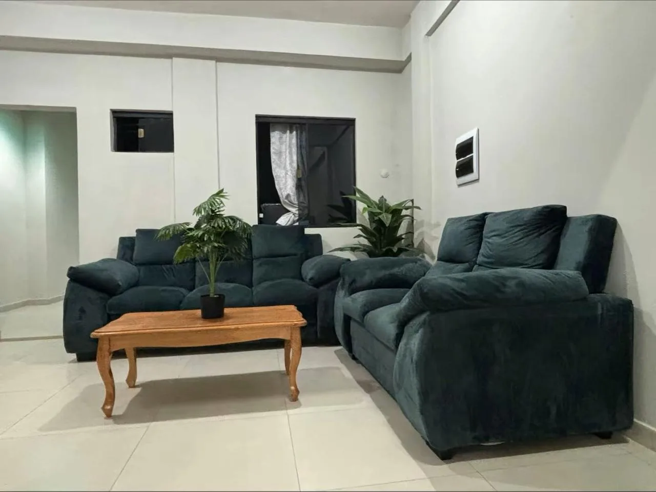 Living común con sillones verdes y mesa de madera